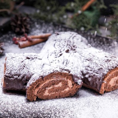 Bûche de Noël – świąteczna czekoladowa rolada w kształcie gałęzi drzewa, posypana cukrem pudrem jak śniegiem