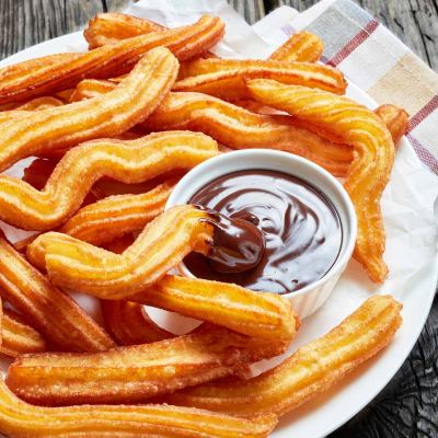 Chrupiące churros, podane na talerzu z sosem czekoladowym