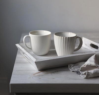 Dwa kubki porcelanowe ustawione na drewnianym stole