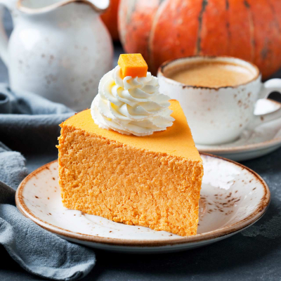 Sernik dyniowy, kremowe ciasto z dodatkiem puree z dyni, udekorowane bitą śmietaną
