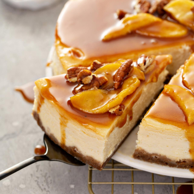 Sernik z kajmakiem na czekoladowym spodzie, udekorowany cząstkami jabłek w karmelu i orzechami